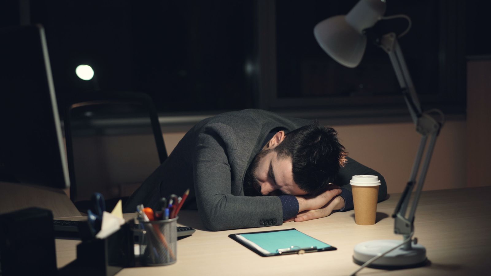 Person am Schreibtisch mit Kaffee, erschöpft am Vormittag